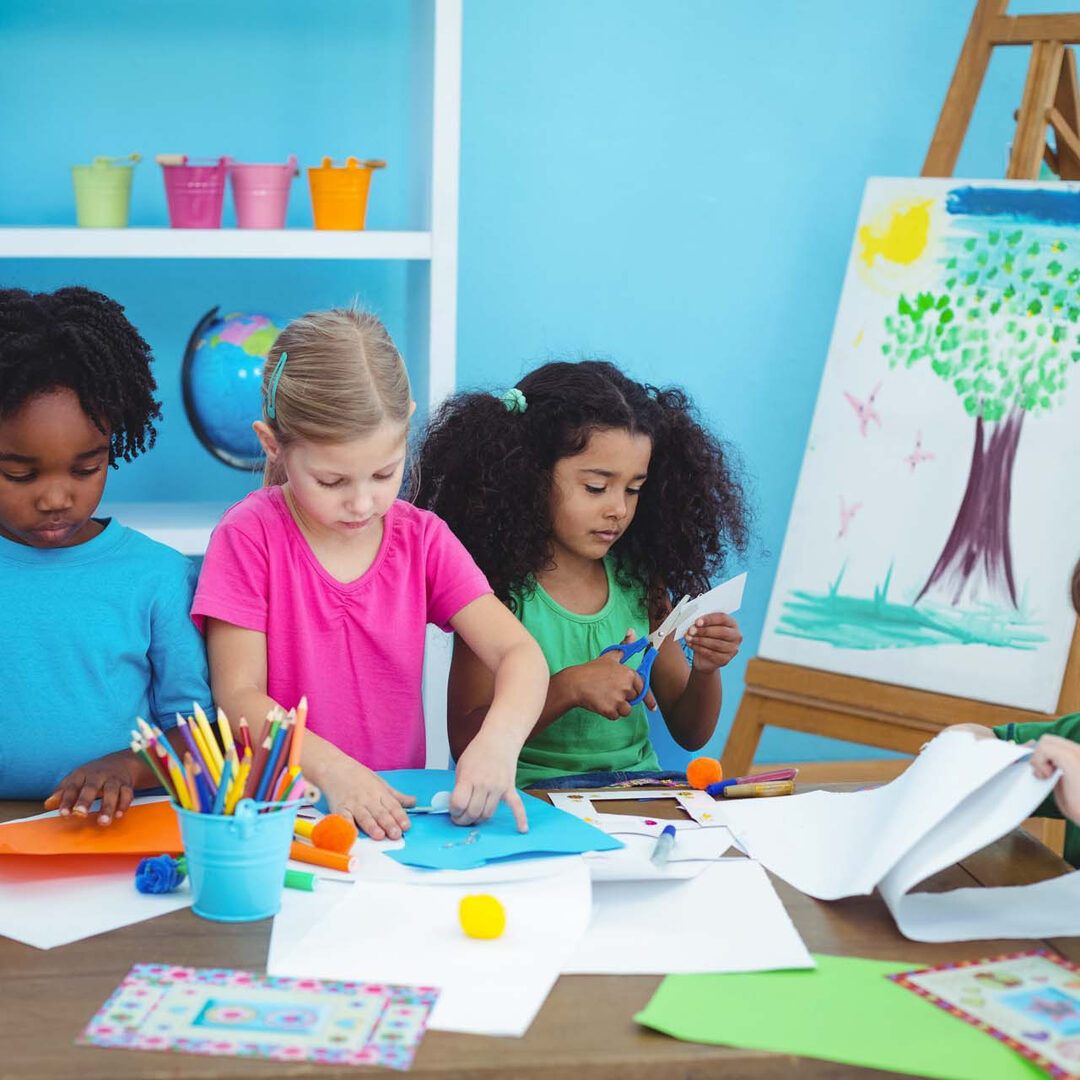 A group of children sitting at a table with art supplies.